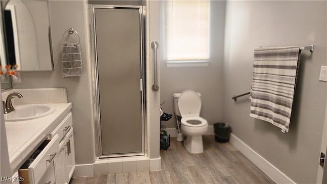 bathroom featuring vanity, wood-type flooring, a shower with door, and toilet