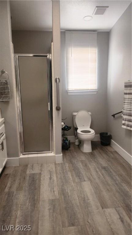 bathroom with toilet, an enclosed shower, and hardwood / wood-style floors