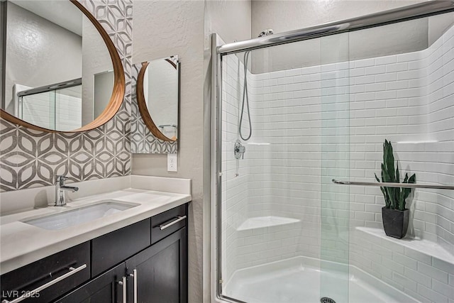 bathroom with decorative backsplash, vanity, and a shower with door