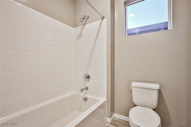 bathroom featuring hardwood / wood-style floors, tiled shower / bath combo, and toilet