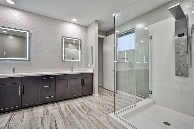 bathroom with vanity, wood-type flooring, a shower with shower door, and tile walls