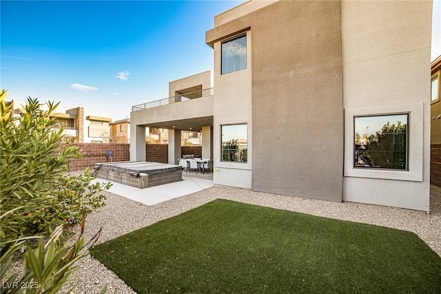 back of house featuring a lawn, a balcony, a patio, and a hot tub