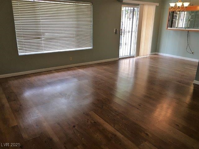 spare room featuring dark hardwood / wood-style flooring and an inviting chandelier