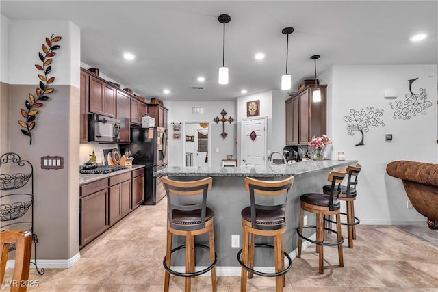 kitchen with a breakfast bar, hanging light fixtures, light stone countertops, kitchen peninsula, and stainless steel appliances