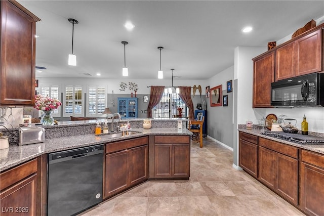 kitchen with dark stone counters, black appliances, sink, decorative light fixtures, and kitchen peninsula