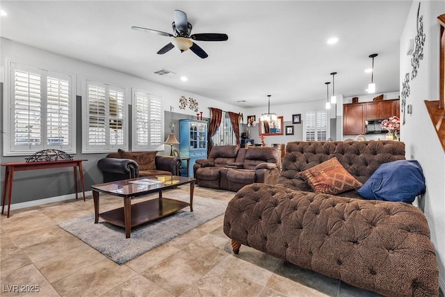 living room featuring ceiling fan with notable chandelier