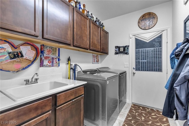 clothes washing area with cabinets, sink, and washer and dryer