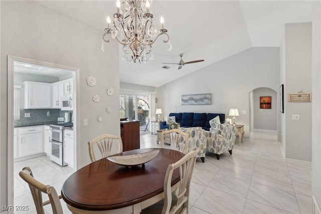 tiled dining area featuring ceiling fan with notable chandelier and lofted ceiling