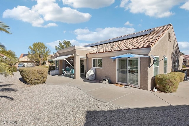 rear view of property with solar panels and a patio