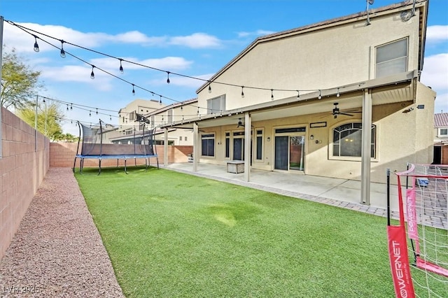 back of house with a lawn, ceiling fan, a trampoline, and a patio