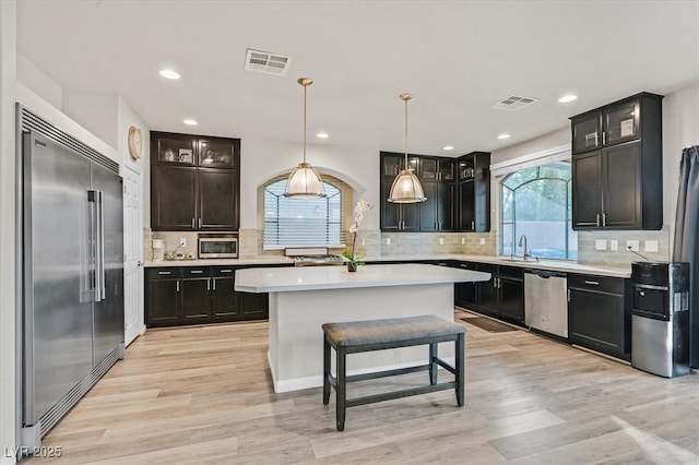 kitchen featuring pendant lighting, plenty of natural light, a center island, and stainless steel appliances