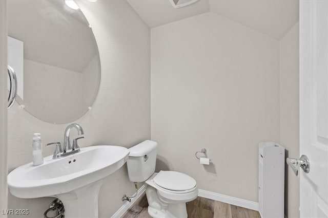 bathroom with hardwood / wood-style flooring, sink, lofted ceiling, and toilet