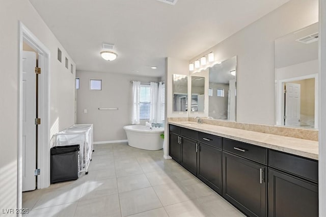 bathroom with a tub to relax in, tile patterned floors, and vanity