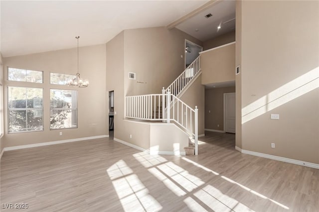 unfurnished living room featuring light wood-type flooring, high vaulted ceiling, and a chandelier