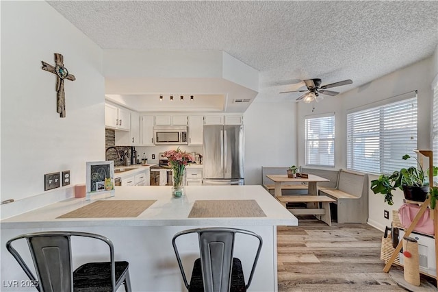 kitchen featuring white cabinets, sink, a textured ceiling, kitchen peninsula, and stainless steel appliances