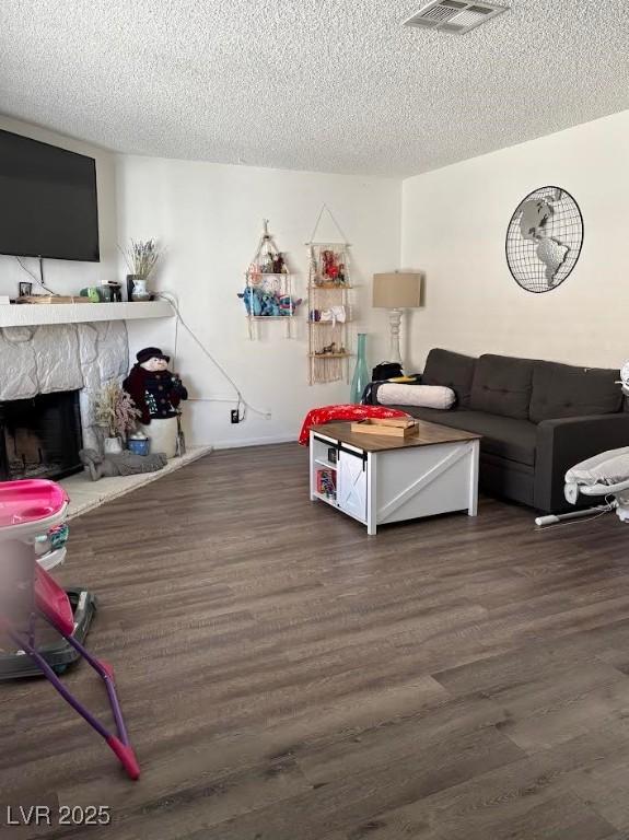 living room featuring a fireplace, dark hardwood / wood-style flooring, and a textured ceiling