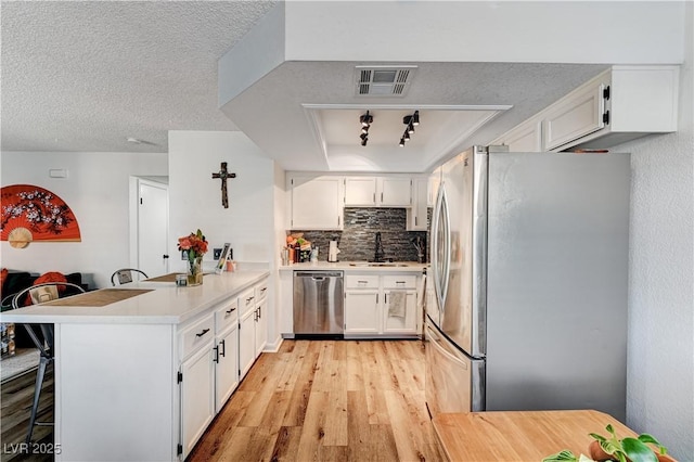 kitchen with a breakfast bar area, kitchen peninsula, white cabinetry, and stainless steel appliances