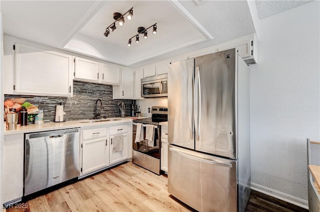 kitchen with white cabinetry, sink, stainless steel appliances, a raised ceiling, and light hardwood / wood-style floors