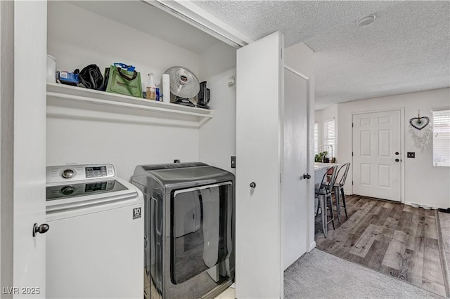 washroom featuring washing machine and clothes dryer, hardwood / wood-style floors, a healthy amount of sunlight, and a textured ceiling