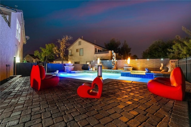 pool at dusk with a patio area and a jacuzzi