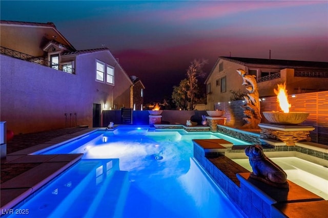 pool at dusk featuring an in ground hot tub and a fire pit