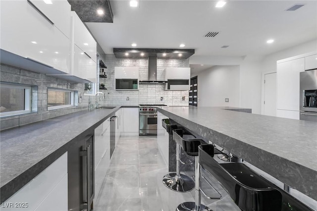 kitchen featuring white cabinetry, wall chimney exhaust hood, stainless steel appliances, and sink