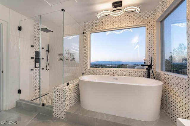 bathroom featuring plus walk in shower, a mountain view, and tile walls