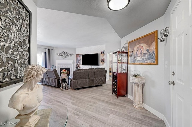 living room featuring vaulted ceiling, a textured ceiling, and light wood-type flooring