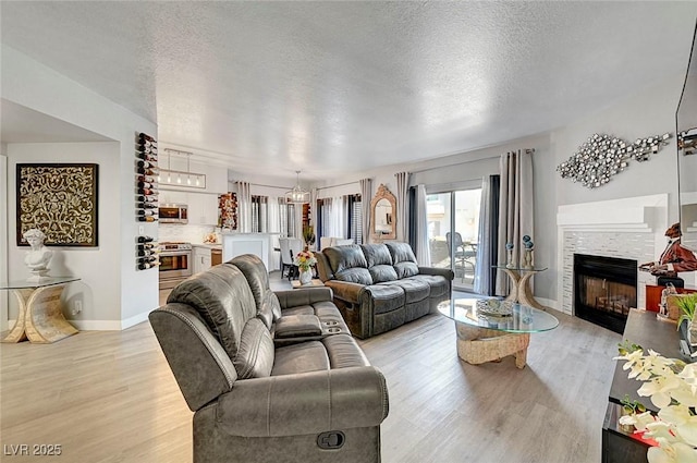 living room with a notable chandelier, light hardwood / wood-style flooring, and a textured ceiling