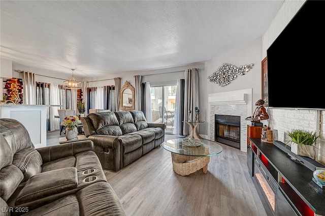 living room featuring light hardwood / wood-style flooring, a fireplace, and a textured ceiling