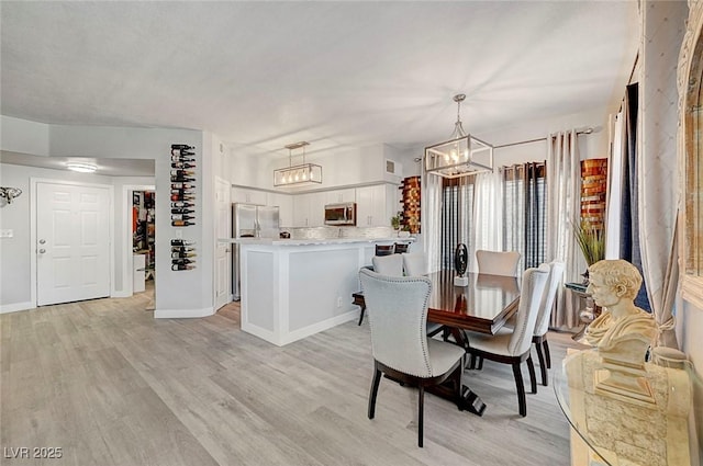 dining room with light hardwood / wood-style flooring and a notable chandelier