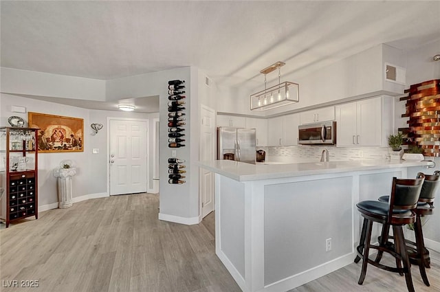 kitchen with decorative light fixtures, kitchen peninsula, white cabinets, and appliances with stainless steel finishes