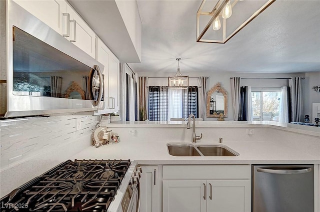 kitchen featuring sink, hanging light fixtures, appliances with stainless steel finishes, a notable chandelier, and white cabinets