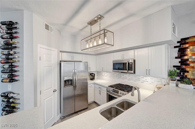 kitchen with pendant lighting, tasteful backsplash, sink, white cabinets, and stainless steel appliances