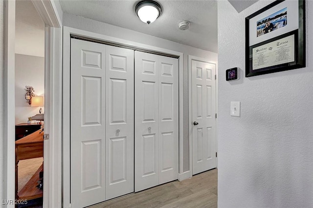 corridor featuring light hardwood / wood-style flooring and a textured ceiling