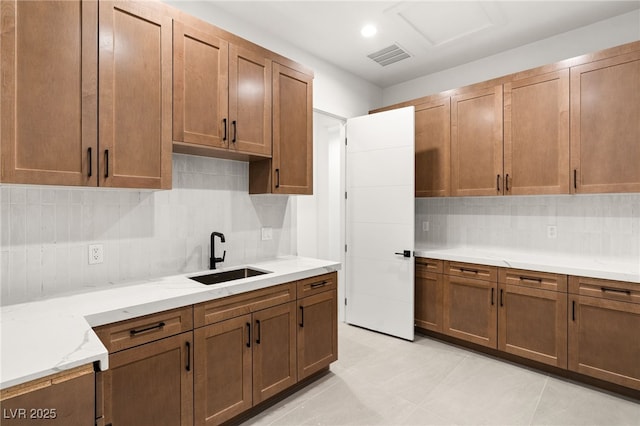 kitchen with light stone countertops, sink, and tasteful backsplash