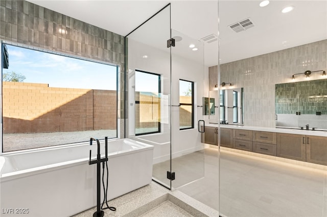 bathroom featuring separate shower and tub, vanity, and tile walls