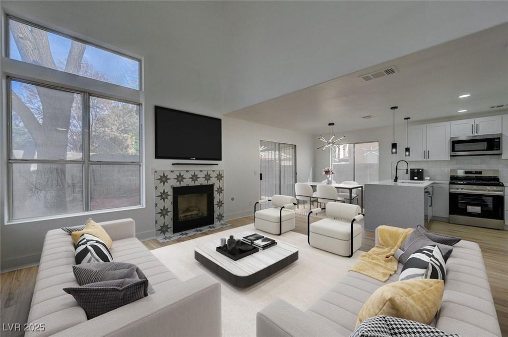 living room featuring a fireplace, sink, a wealth of natural light, and a chandelier