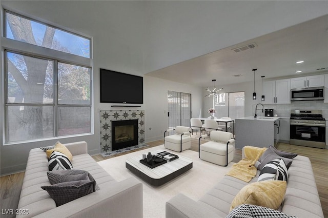 living room featuring a fireplace, sink, a wealth of natural light, and a chandelier