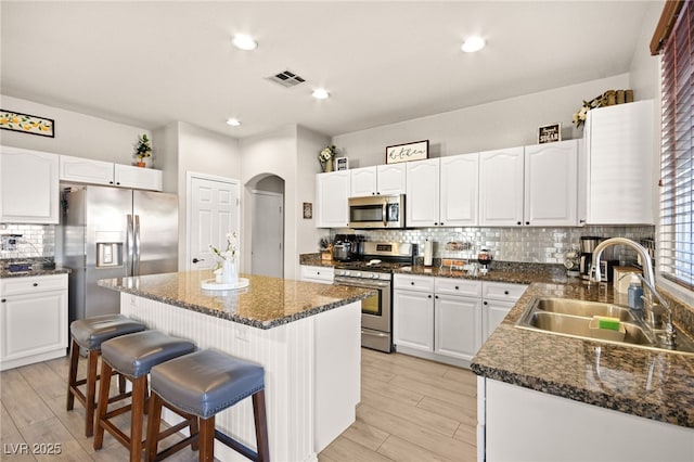 kitchen with a breakfast bar, a center island, sink, white cabinetry, and stainless steel appliances