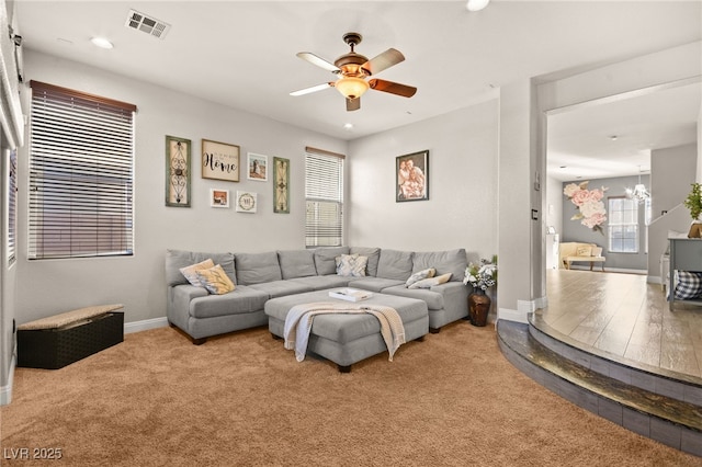 living room with plenty of natural light, carpet floors, and ceiling fan with notable chandelier