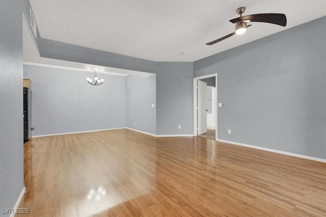 unfurnished room with light hardwood / wood-style flooring, brick wall, and ceiling fan with notable chandelier