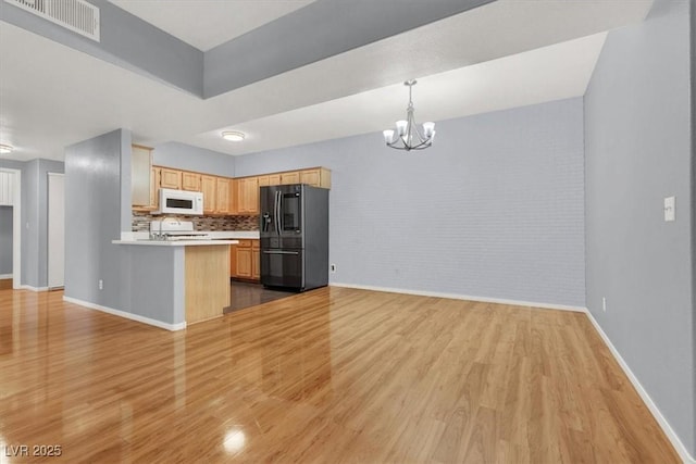 kitchen featuring tasteful backsplash, stainless steel fridge with ice dispenser, kitchen peninsula, decorative light fixtures, and light brown cabinetry