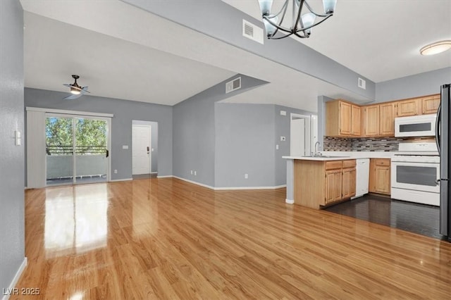 kitchen featuring pendant lighting, white appliances, backsplash, ceiling fan with notable chandelier, and kitchen peninsula