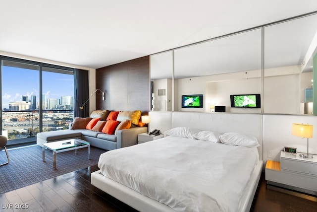 bedroom with floor to ceiling windows and dark hardwood / wood-style flooring