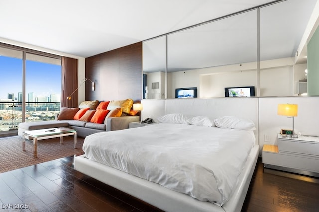 bedroom with access to outside, dark hardwood / wood-style floors, and a wall of windows