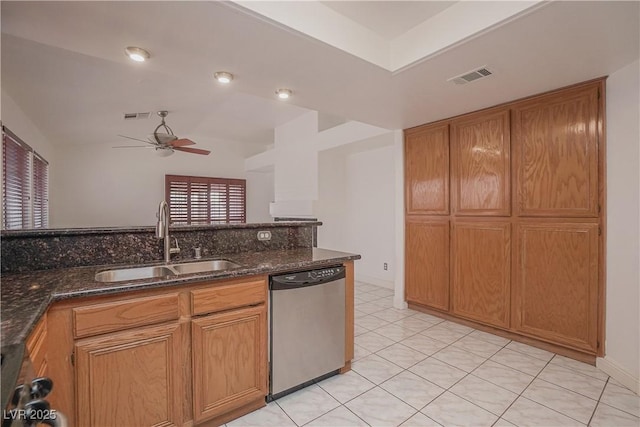 kitchen with stainless steel dishwasher, ceiling fan, dark stone counters, and sink