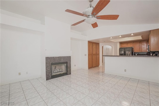 unfurnished living room featuring ceiling fan, lofted ceiling, and a tiled fireplace