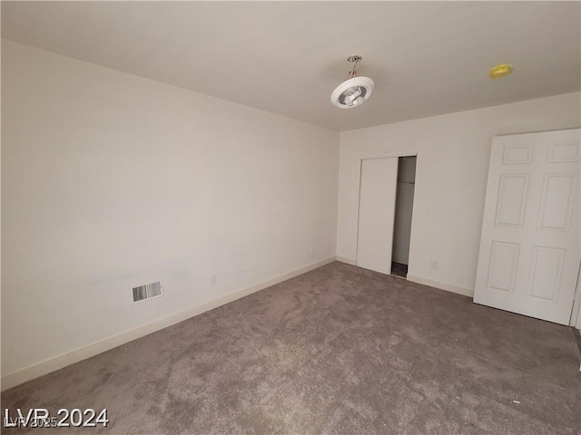 unfurnished bedroom with a closet and dark colored carpet