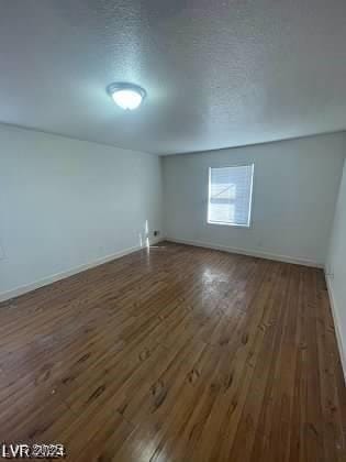 additional living space featuring a textured ceiling and dark hardwood / wood-style flooring